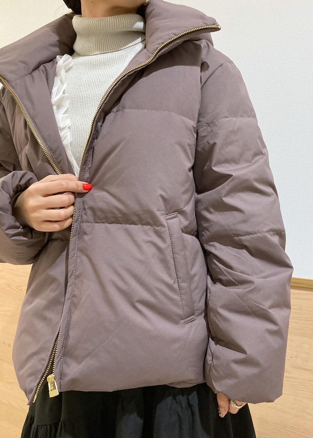 ブラウン系のダウンジャケット/コート、グレー系のニット/セーター、ブラック系のブーツを着用したレディースの冬コーディネートの2枚目の写真