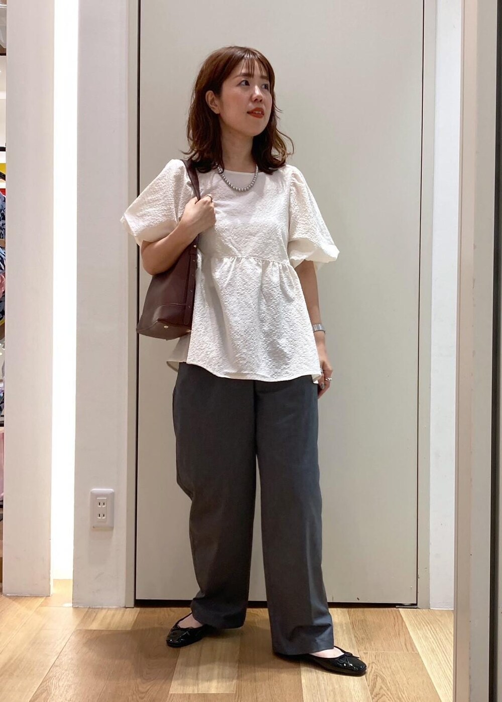 ブラック系のバレエシューズ、グレー系のチノパンツ、ホワイト系のシャツ/ブラウスを着用したレディースの夏コーディネートの2枚目の写真