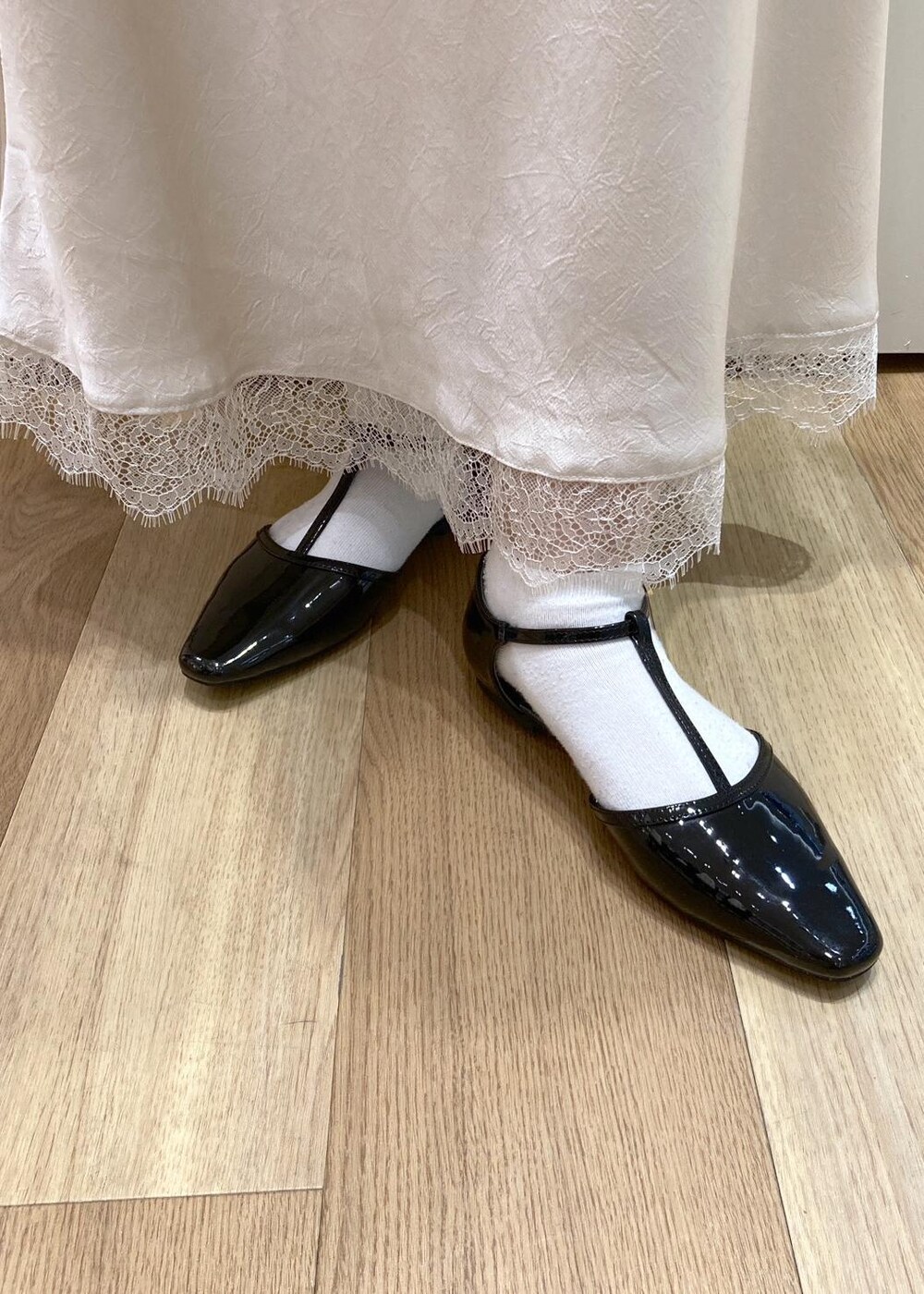 ブラック系のパンプス、ベージュ系のショルダーバッグ、ホワイト系のスカートを着用したレディースの春コーディネートの9枚目の写真