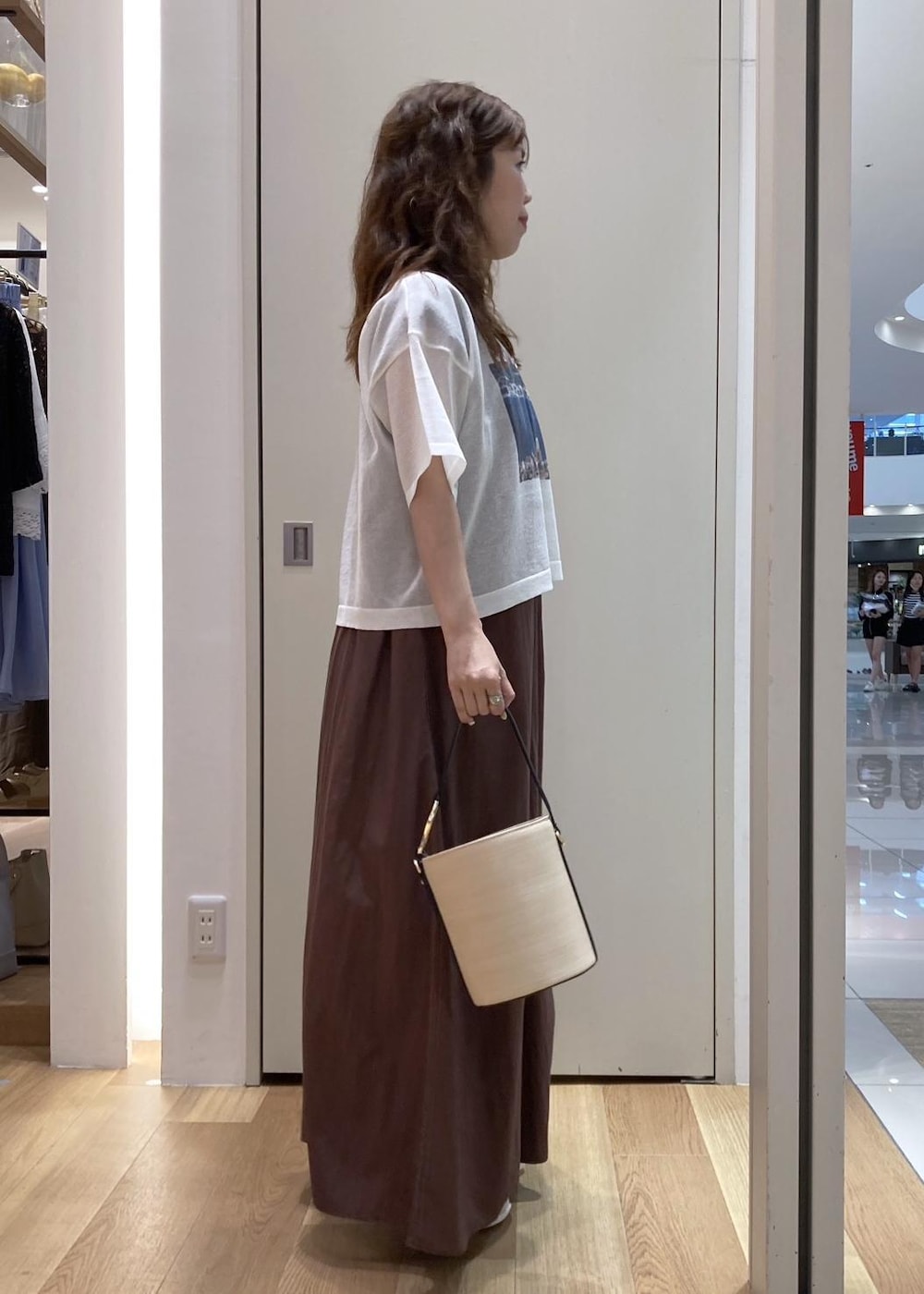 ホワイト系のサンダル、ブラック系のハンドバッグ、ブラウン系のワンピースを着用したレディースの夏コーディネートの2枚目の写真