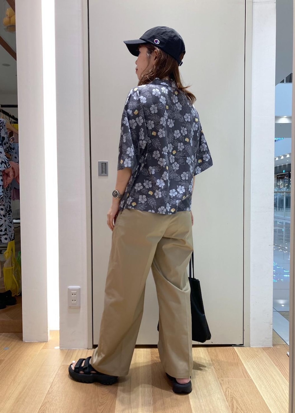 ブラック系のトートバッグ、ブラック系のサンダル、グレー系のチノパンツを着用したレディースの夏コーディネートの4枚目の写真