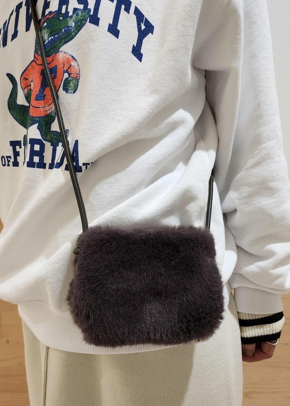 ホワイト系のジャンパースカート、ホワイト系のニット/セーター、グレー系のショルダーバッグを着用したレディースの秋コーディネートの5枚目の写真