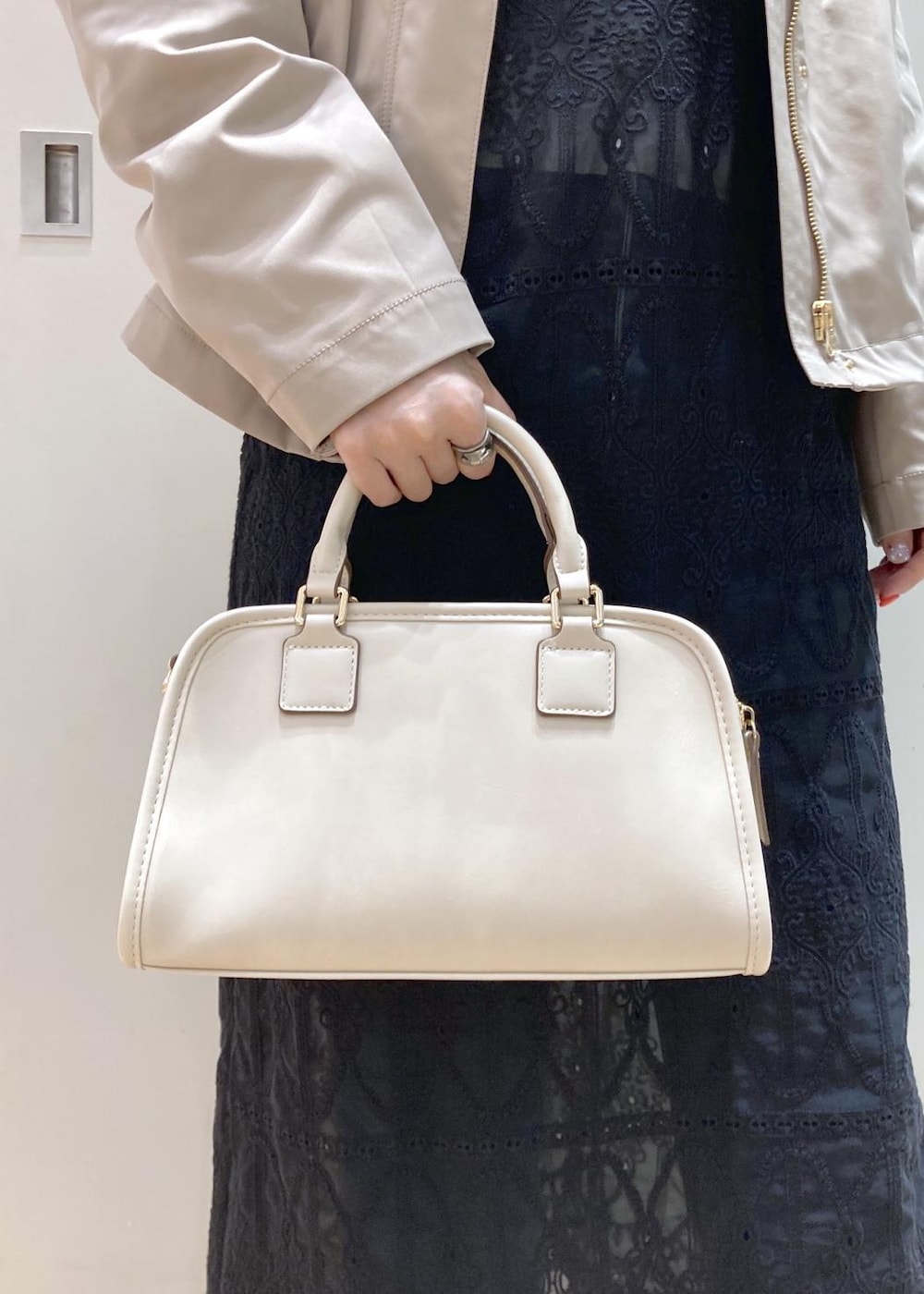 ホワイト系のボストンバッグ、ブルー系のデニムパンツ、ブラック系のワンピースを着用したレディースの春コーディネートの10枚目の写真