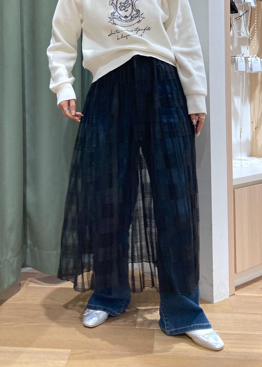 ブルー系のデニムパンツ、ブラック系のスカート、グリーン系のマウンテンパーカーを着用したレディースの春コーディネートの7枚目の写真