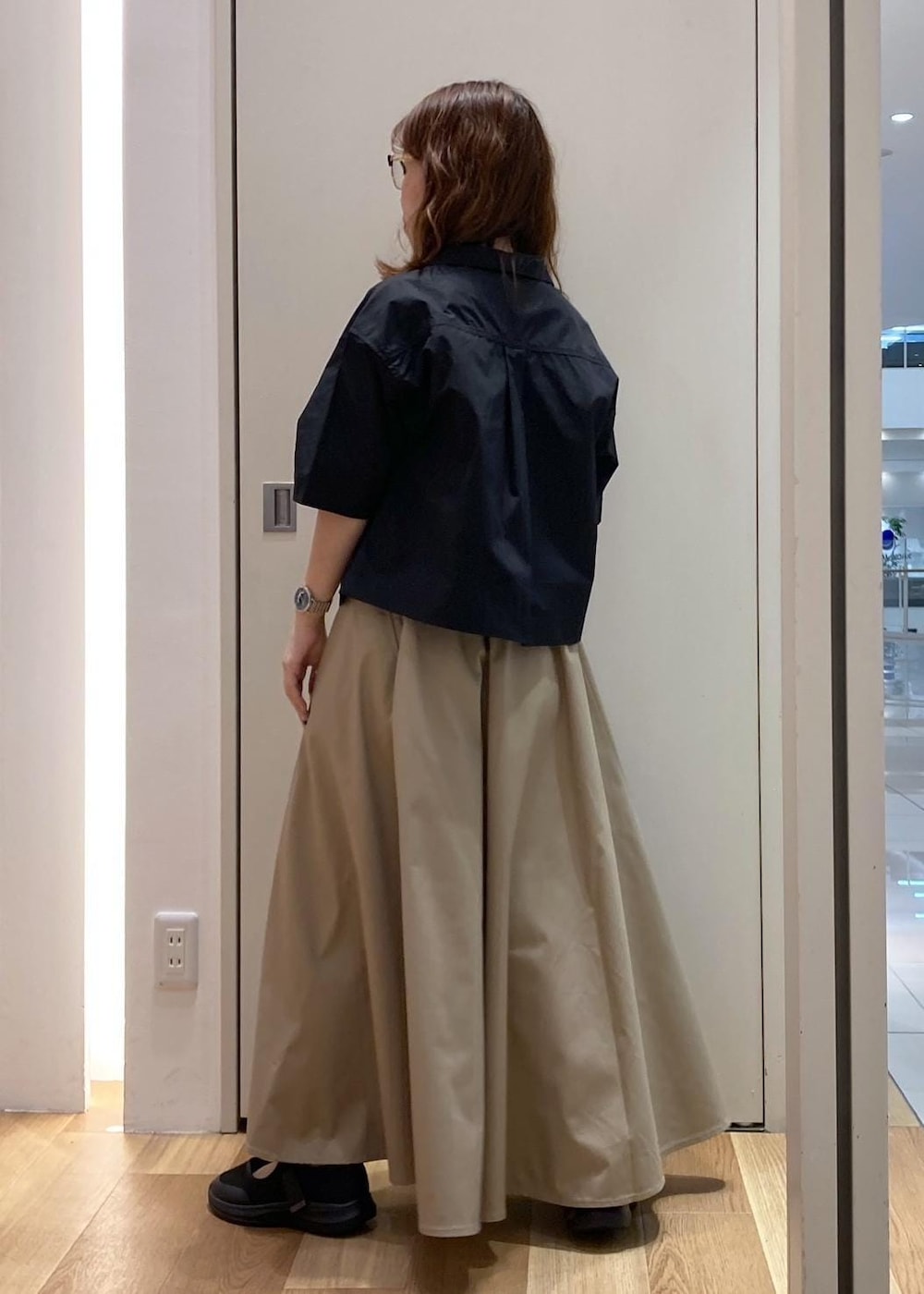 ブラック系のスニーカー、ベージュ系のスカート、ブラック系のシャツ/ブラウスを着用したレディースの夏コーディネートの3枚目の写真