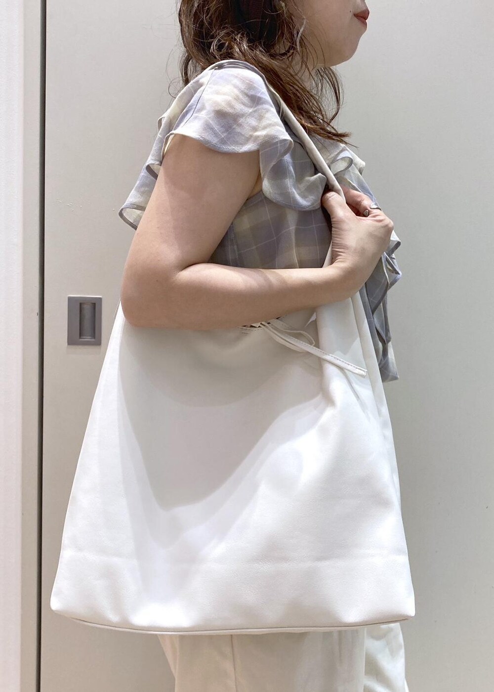 ホワイト系のトートバッグ、ブラウン系のパンプス、ホワイト系のチノパンツを着用したレディースの夏コーディネートの6枚目の写真