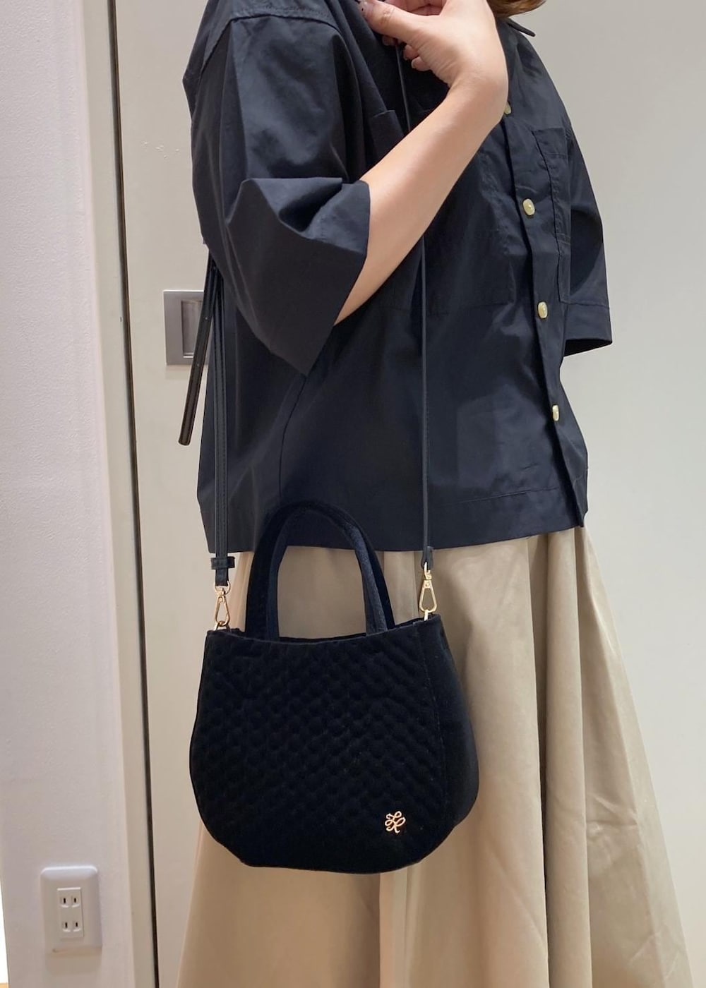 ブラック系のスニーカー、ベージュ系のスカート、ブラック系のシャツ/ブラウスを着用したレディースの夏コーディネートの8枚目の写真