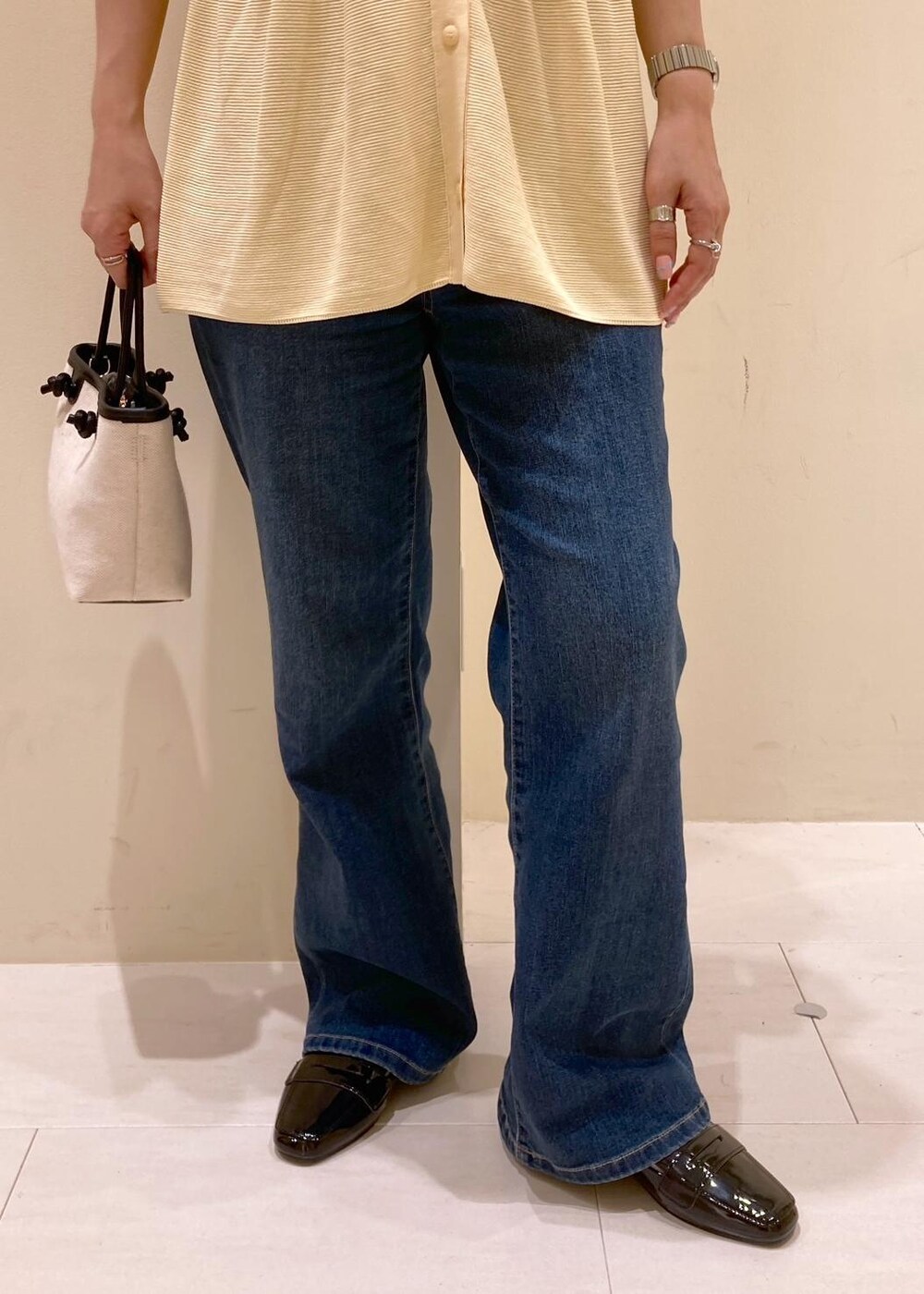 ブルー系のデニムパンツ、ブラック系のトートバッグ、ベージュ系のカーディガン/ボレロを着用したレディースの夏コーディネートの6枚目の写真