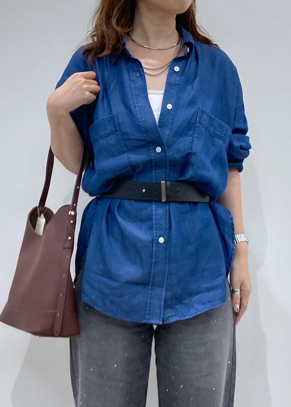 レッド系のショルダーバッグ、ブルー系のシャツ/ブラウス、ブラック系のデニムパンツを着用したレディースの夏コーディネートの5枚目の写真