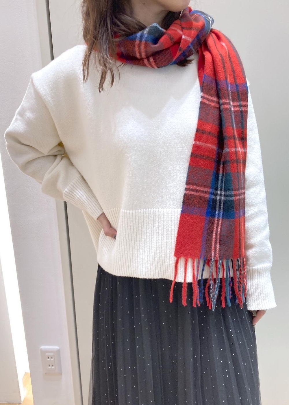 ブラック系のスカート、ホワイト系のニット/セーター、ブラック系のブーツを着用したレディースの冬コーディネートの4枚目の写真