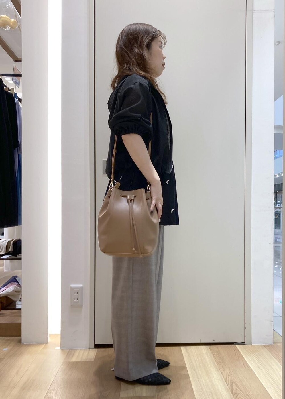 ベージュ系のスラックス、ブラウン系のショルダーバッグ、ブラック系のサンダルを着用したレディースの春コーディネートの2枚目の写真