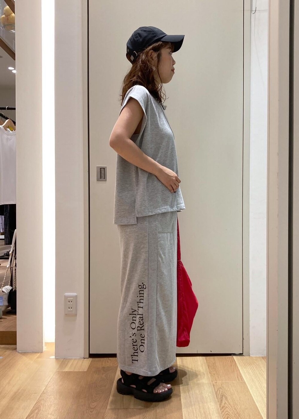 ブラック系のサンダル、レッド系のトートバッグ、グレー系のスカートを着用したレディースの夏コーディネートの2枚目の写真