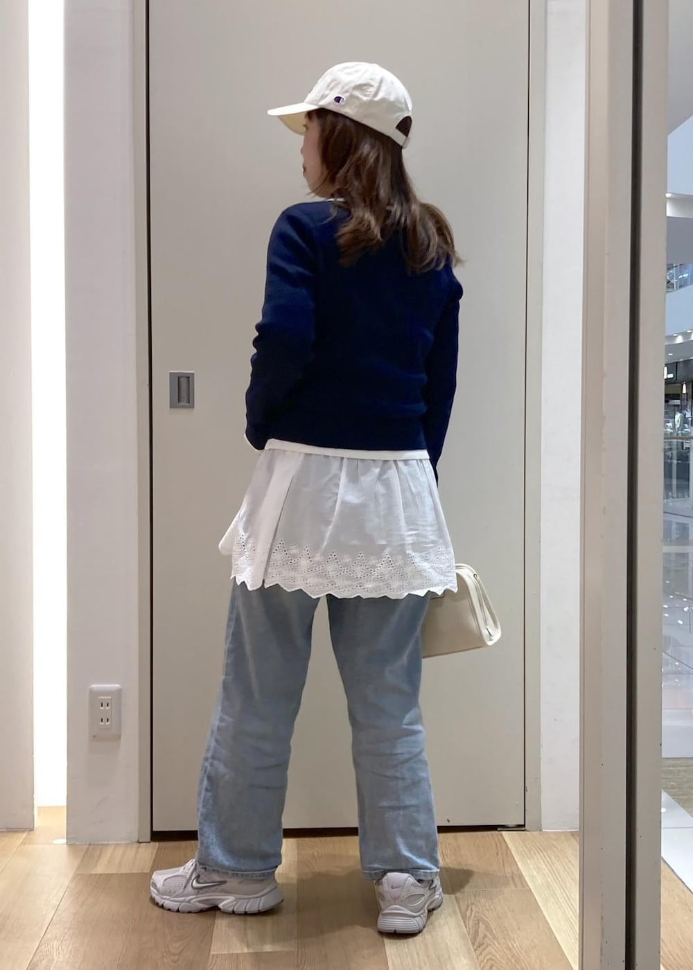 ブルー系のデニムパンツ、ホワイト系のボストンバッグ、ブルー系のニット/セーターを着用したレディースの冬コーディネートの3枚目の写真