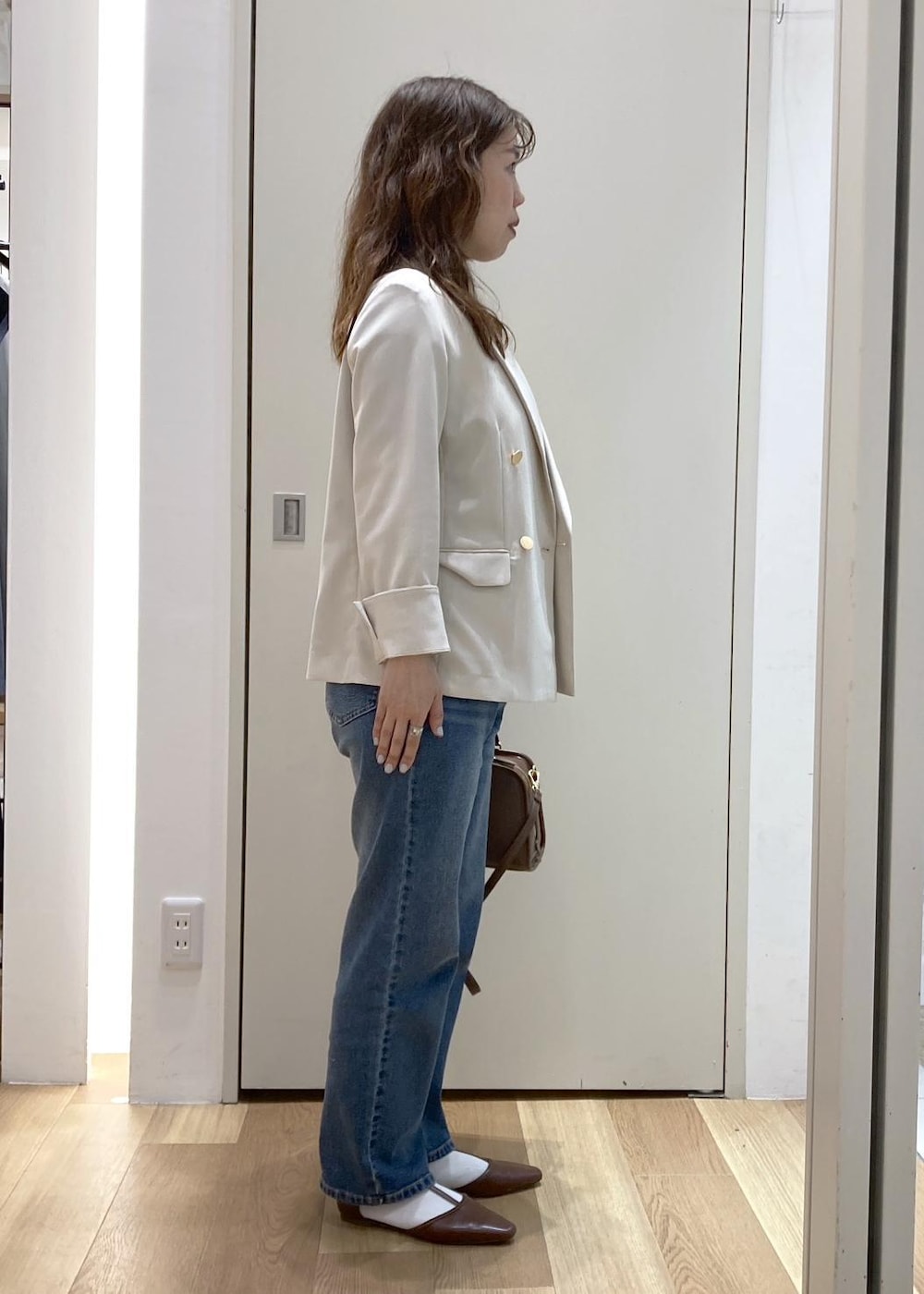ブラウン系のボストンバッグ、ブルー系のデニムパンツ、ブラウン系のパンプスを着用したレディースの春コーディネートの2枚目の写真