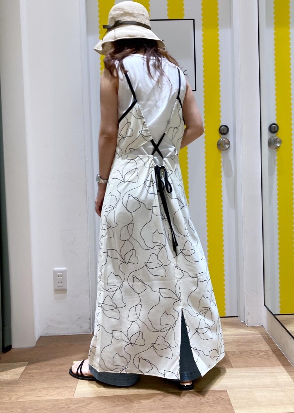 ホワイト系のワンピース、ベージュ系のTシャツ/カットソー、ブラック系のサンダルを着用したレディースの春コーディネートの2枚目の写真