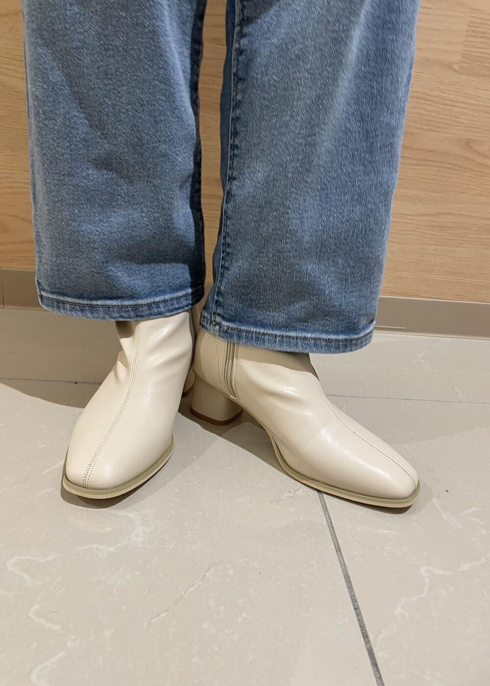 ホワイト系のブーツ、ホワイト系のトートバッグ、ブルー系のデニムパンツを着用したレディースの冬コーディネートの6枚目の写真