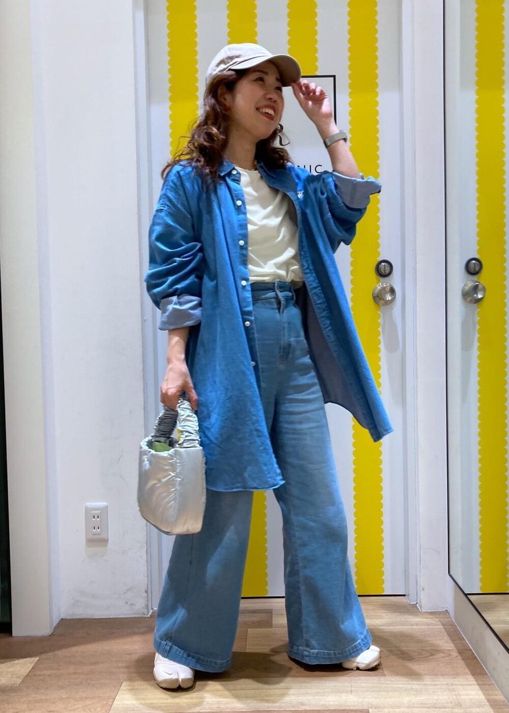 ホワイト系のTシャツ/カットソー、ブルー系のデニムパンツ、シルバー系のショルダーバッグを着用したレディースの春コーディネートの2枚目の写真