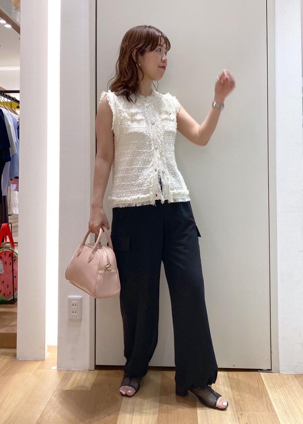 ピンク系のボストンバッグ、ブラック系のパンプス、ブラック系のカーゴパンツを着用したレディースの夏コーディネートの2枚目の写真