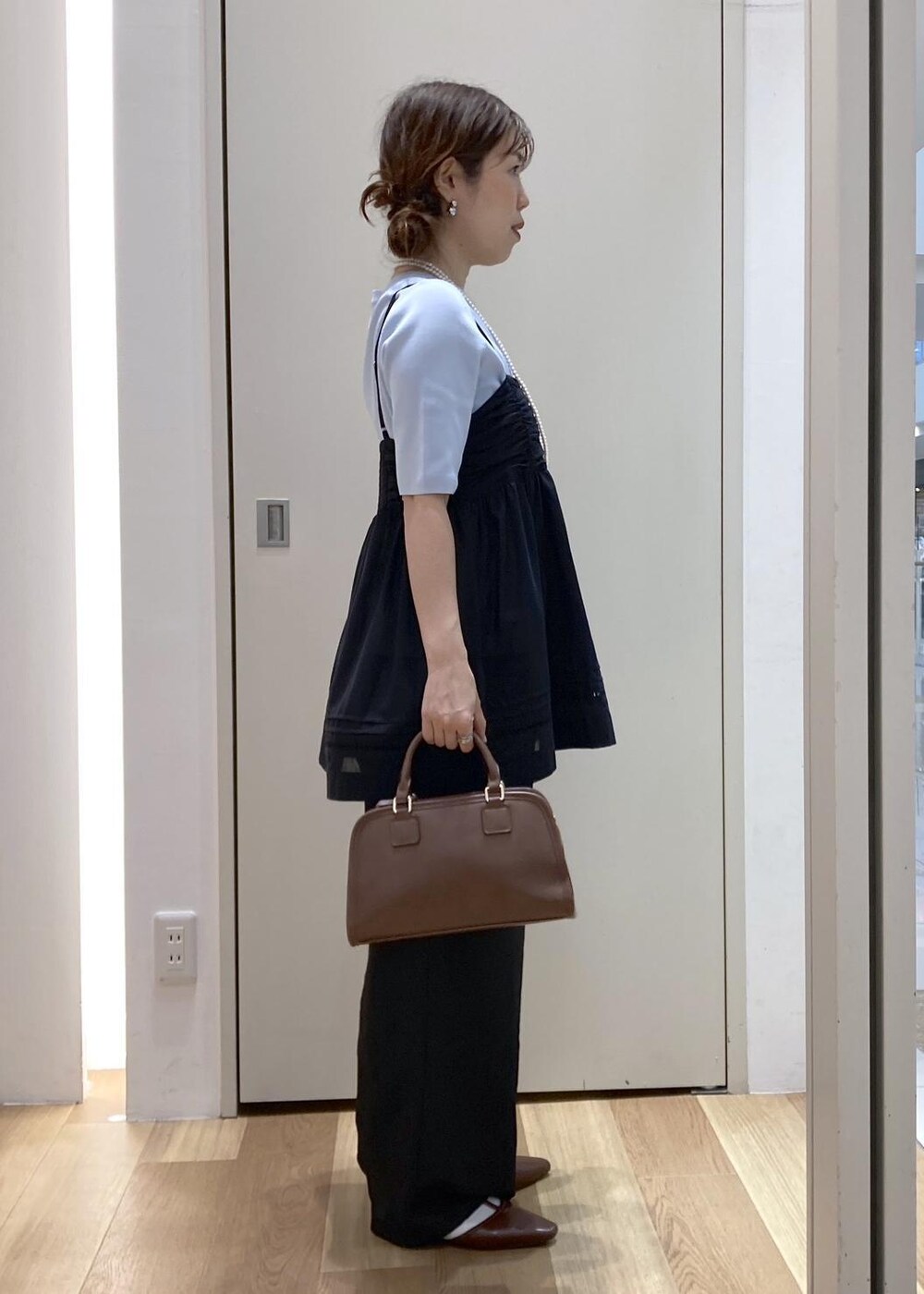 ブラウン系のボストンバッグ、ブラウン系のパンプス、ブラック系のシャツ/ブラウスを着用したレディースの春コーディネートの2枚目の写真