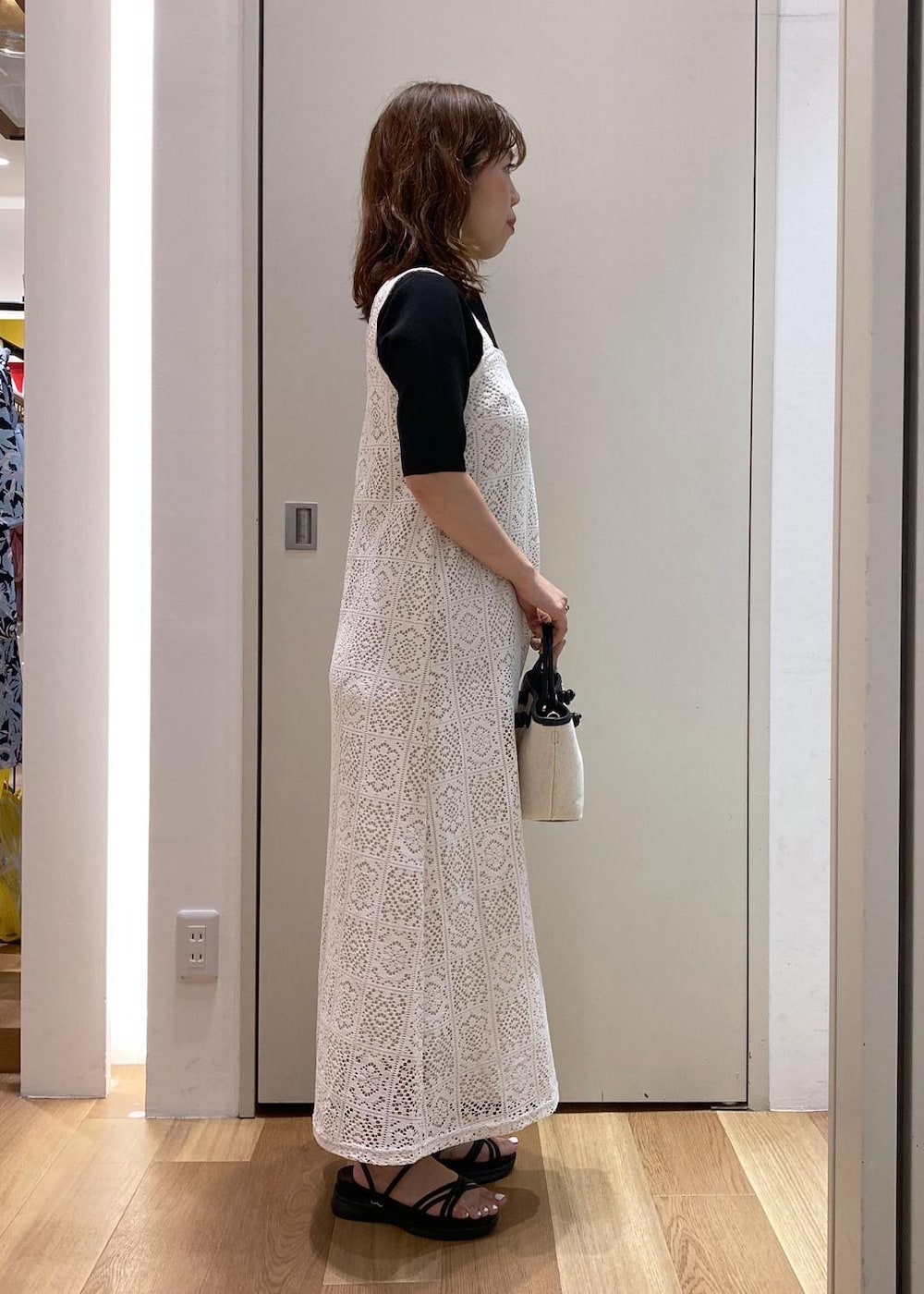 ブラック系のニット/セーター、ブラック系のトートバッグ、ブラック系のサンダルを着用したレディースの夏コーディネートの2枚目の写真