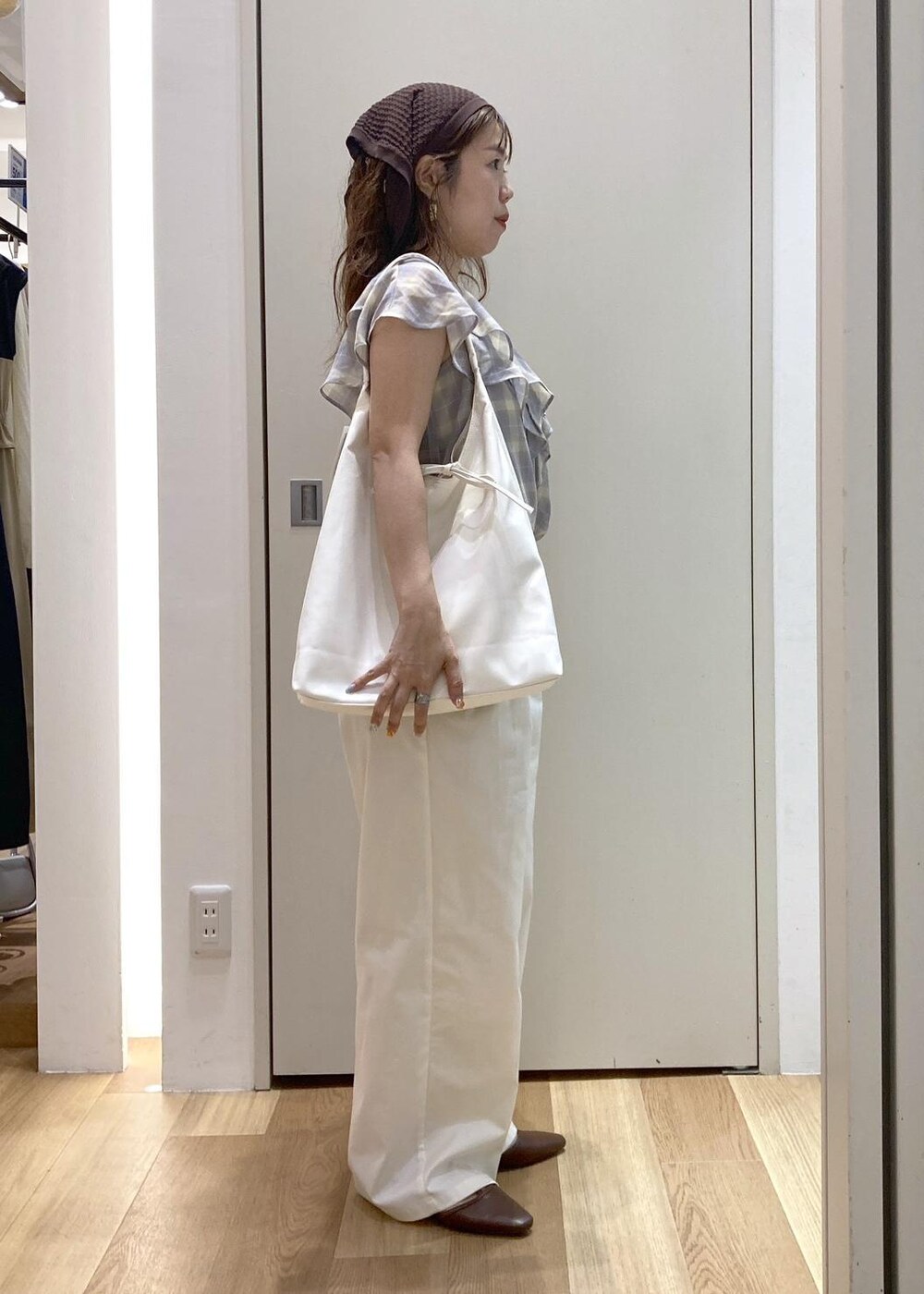 ホワイト系のトートバッグ、ブラウン系のパンプス、ホワイト系のチノパンツを着用したレディースの夏コーディネートの2枚目の写真