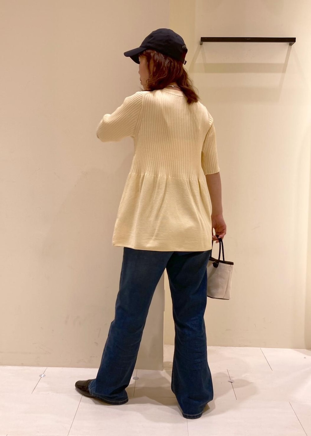 ブルー系のデニムパンツ、ブラック系のトートバッグ、ベージュ系のカーディガン/ボレロを着用したレディースの夏コーディネートの4枚目の写真