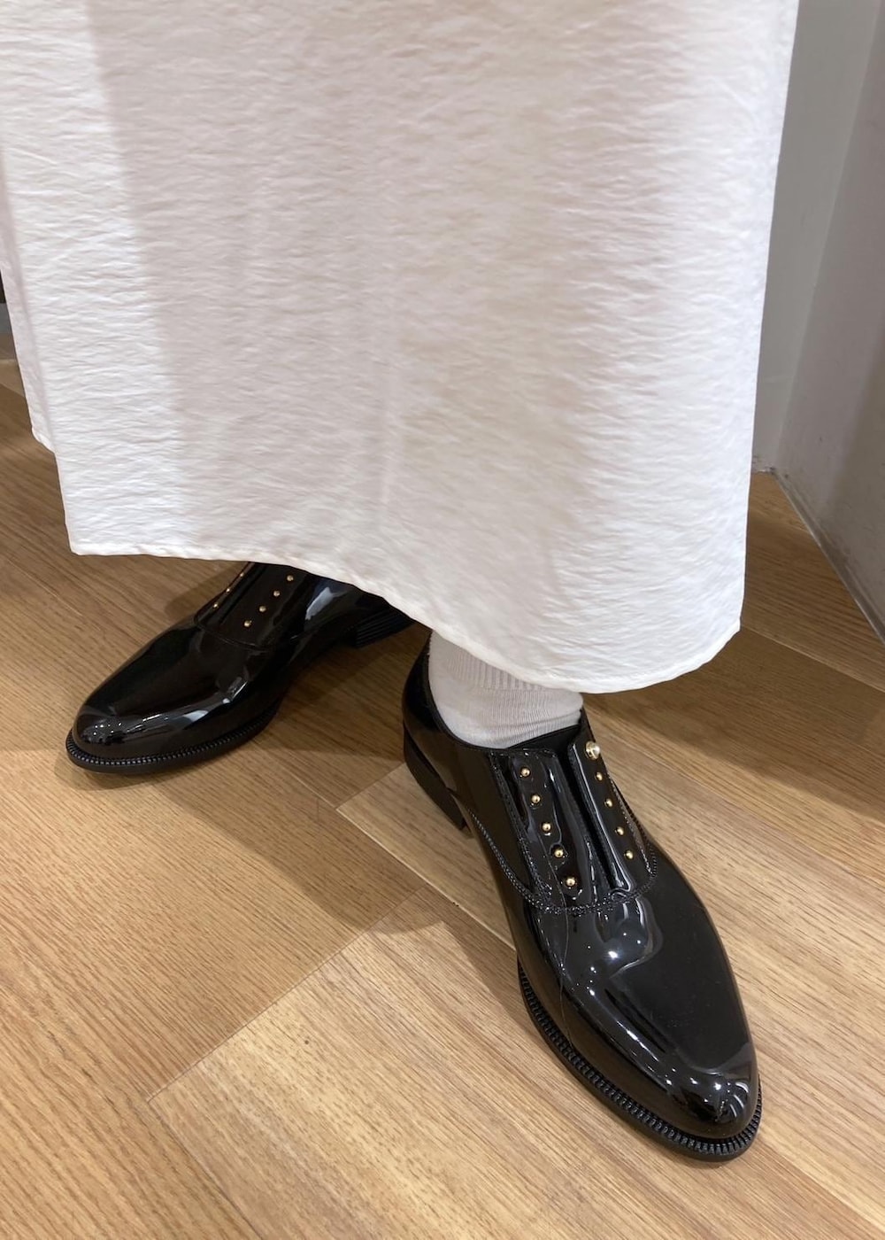 ホワイト系のワンピース、ブラック系のレインシューズ、ホワイト系のベストを着用したレディースの春コーディネートの10枚目の写真