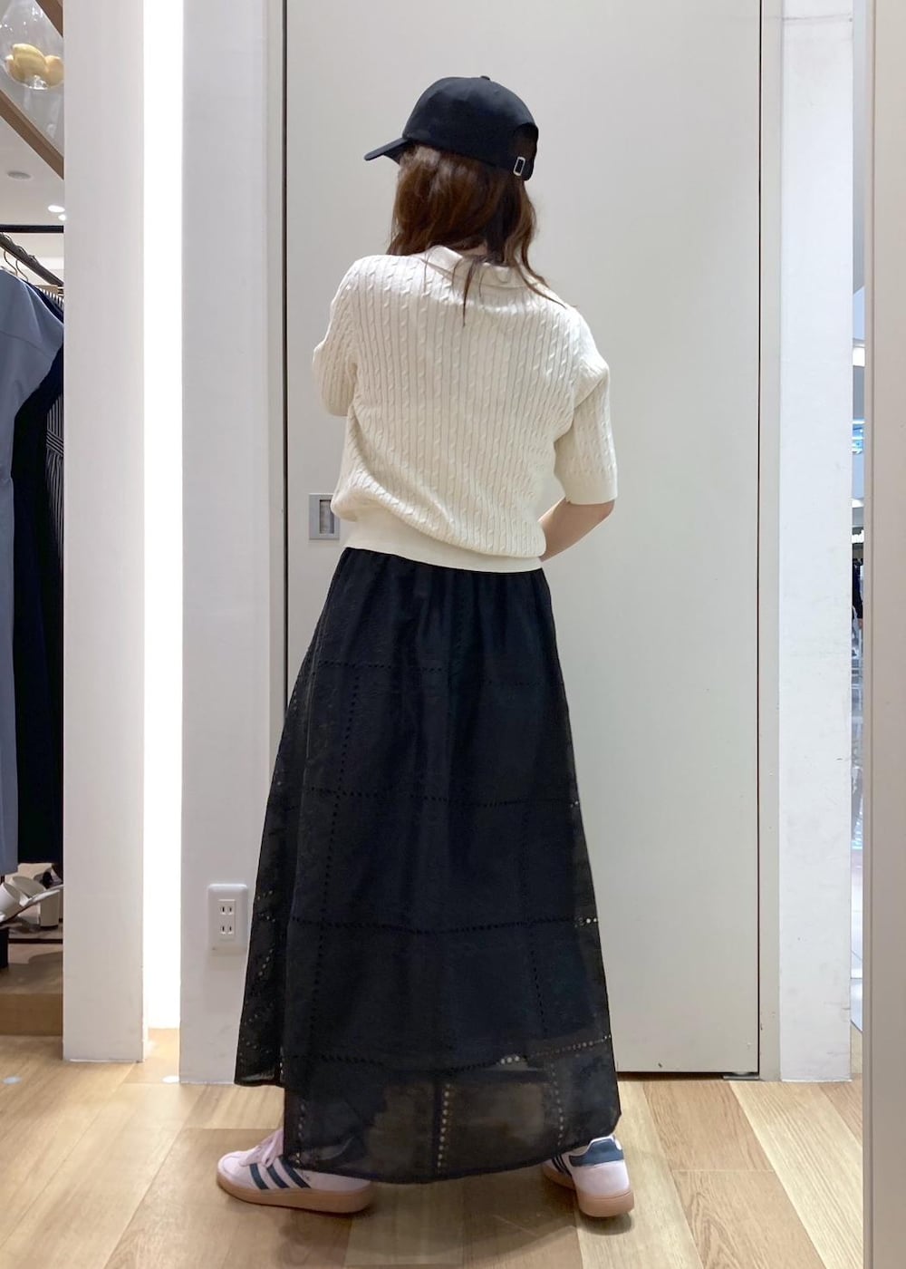 ブラック系のバックパック/リュック、ブラック系のスカート、ホワイト系のニット/セーターを着用したレディースの春コーディネートの3枚目の写真