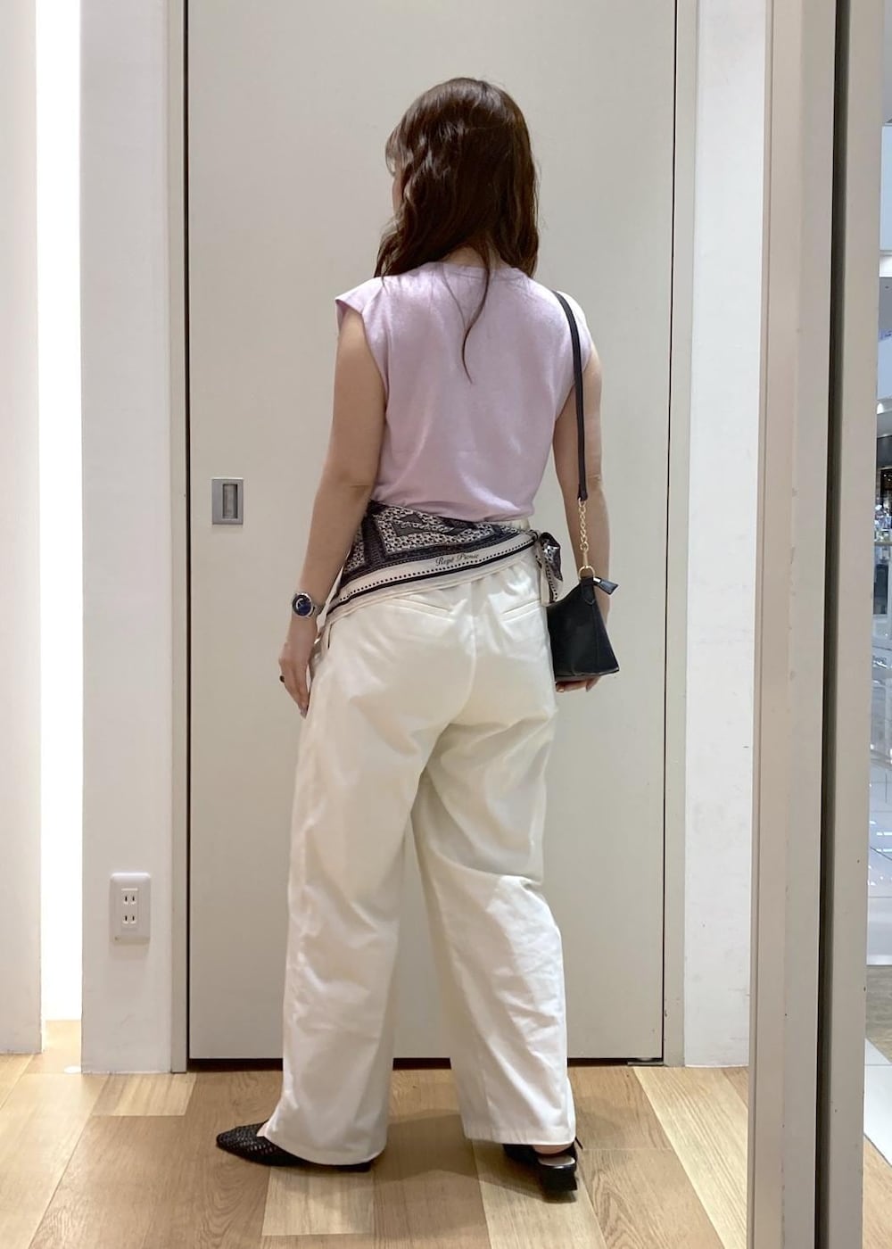 ホワイト系のチノパンツ、ブラック系のパンプス、ブラック系のショルダーバッグを着用したレディースの夏コーディネートの3枚目の写真