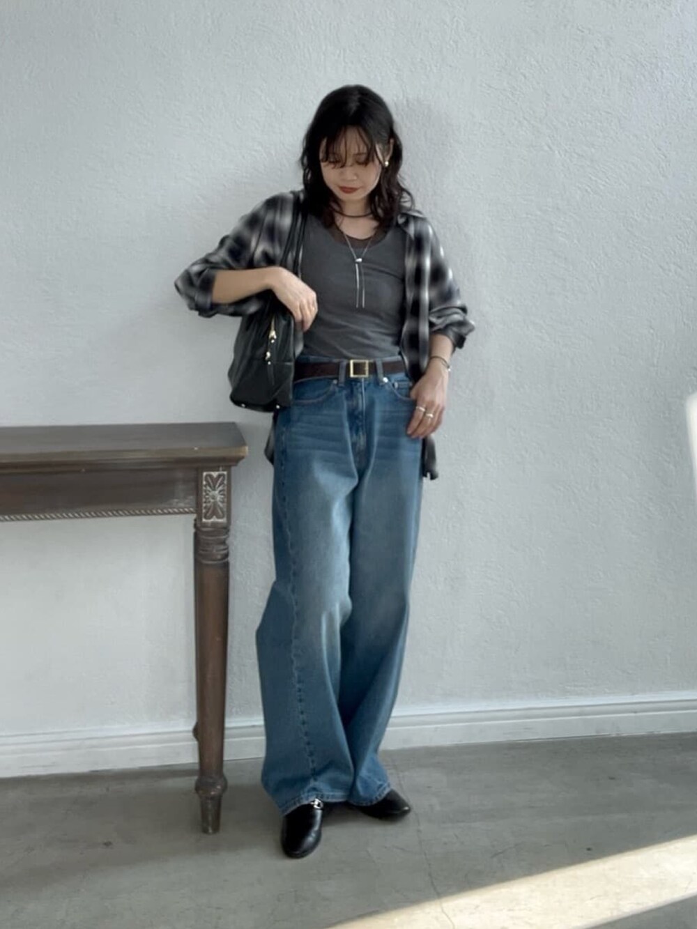 ブルー系のデニムパンツ、ブラック系のローファー、ブラック系のボストンバッグを着用したレディースの夏コーディネートの2枚目の写真