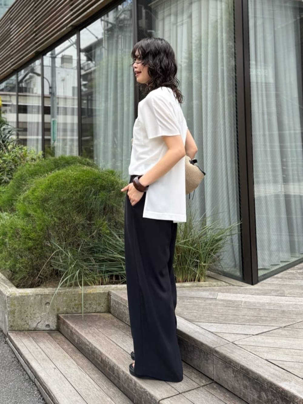 ブラック系のスラックス、ホワイト系のシャツ/ブラウス、ブラック系のトートバッグを着用したレディースの夏コーディネートの3枚目の写真