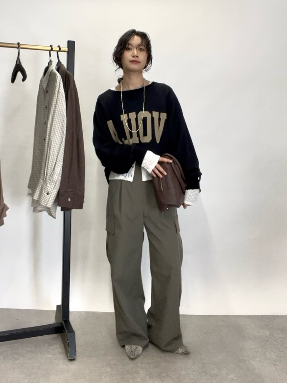 グリーン系のカーゴパンツ、グレー系のパンプス、ブラウン系のボストンバッグを着用したレディースの秋コーディネートの2枚目の写真