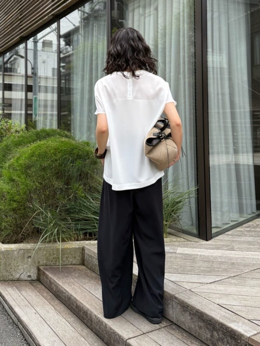 ブラック系のスラックス、ホワイト系のシャツ/ブラウス、ブラック系のトートバッグを着用したレディースの夏コーディネートの4枚目の写真