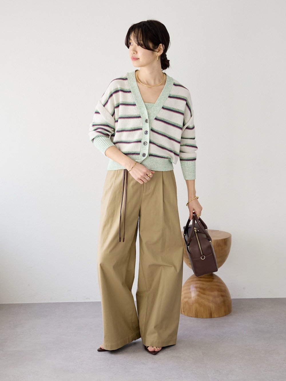 ベージュ系のチノパンツ、ブラウン系のボストンバッグ、ホワイト系のキャミソールを着用したレディースの冬コーディネートの2枚目の写真