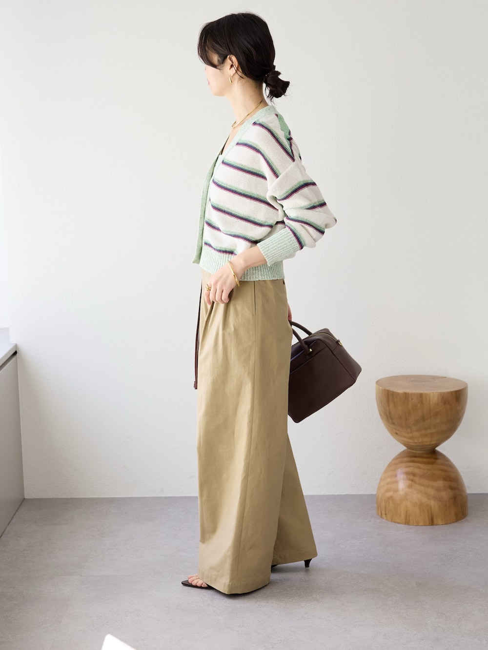 ベージュ系のチノパンツ、ブラウン系のボストンバッグ、ホワイト系のキャミソールを着用したレディースの冬コーディネートの3枚目の写真