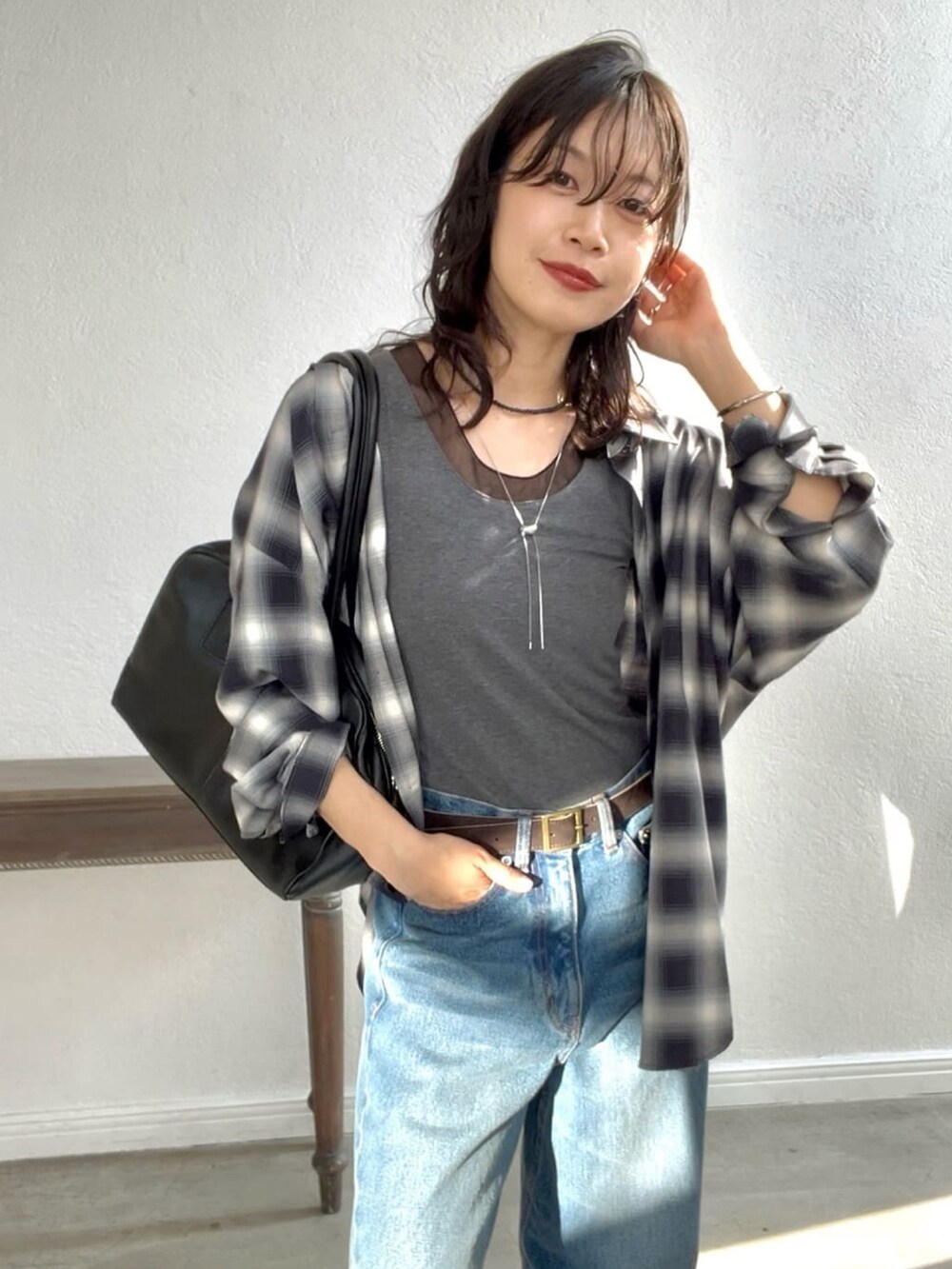 ブルー系のデニムパンツ、ブラック系のローファー、ブラック系のボストンバッグを着用したレディースの夏コーディネートの5枚目の写真