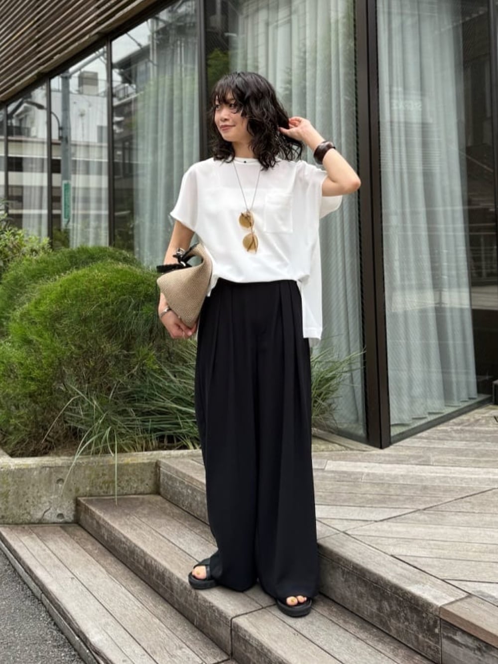 ブラック系のスラックス、ホワイト系のシャツ/ブラウス、ブラック系のトートバッグを着用したレディースの夏コーディネートの2枚目の写真