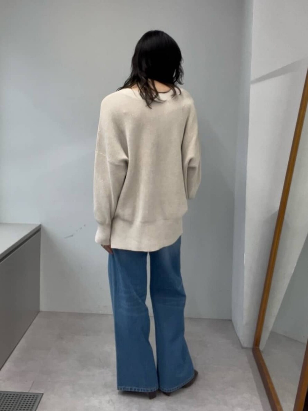 ブルー系のデニムパンツ、ホワイト系のニット/セーター、ブラウン系のブーツを着用したレディースの秋コーディネートの3枚目の写真