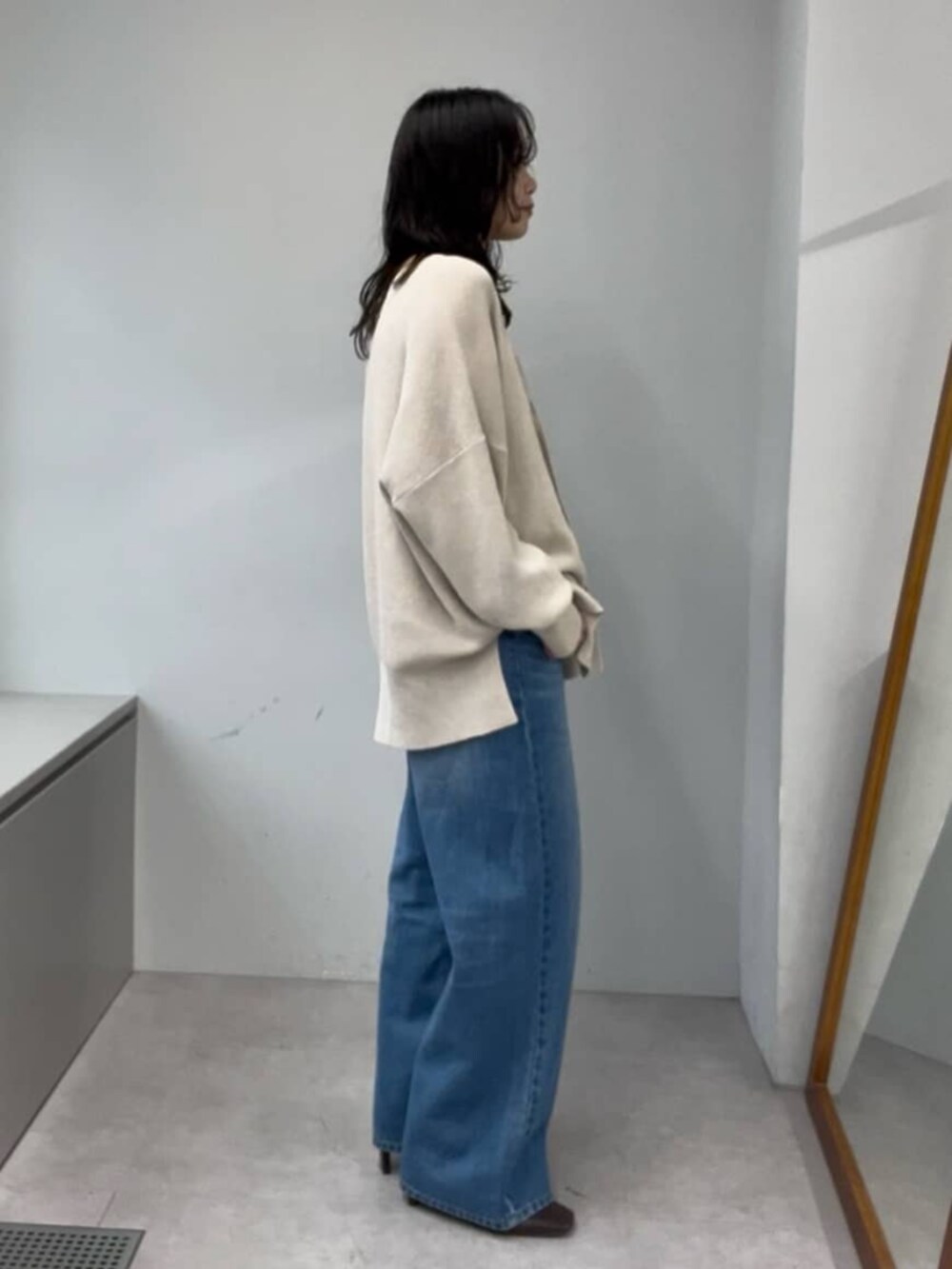 ブルー系のデニムパンツ、ホワイト系のニット/セーター、ブラウン系のブーツを着用したレディースの秋コーディネートの2枚目の写真