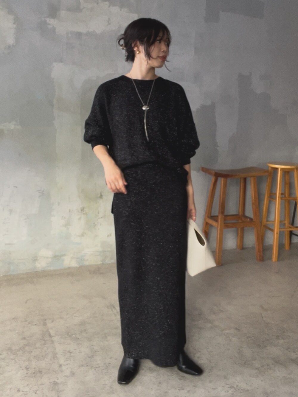 ブラック系のニット/セーター、ブラック系のスカート、ホワイト系のハンドバッグを着用したレディースの秋コーディネートの4枚目の写真