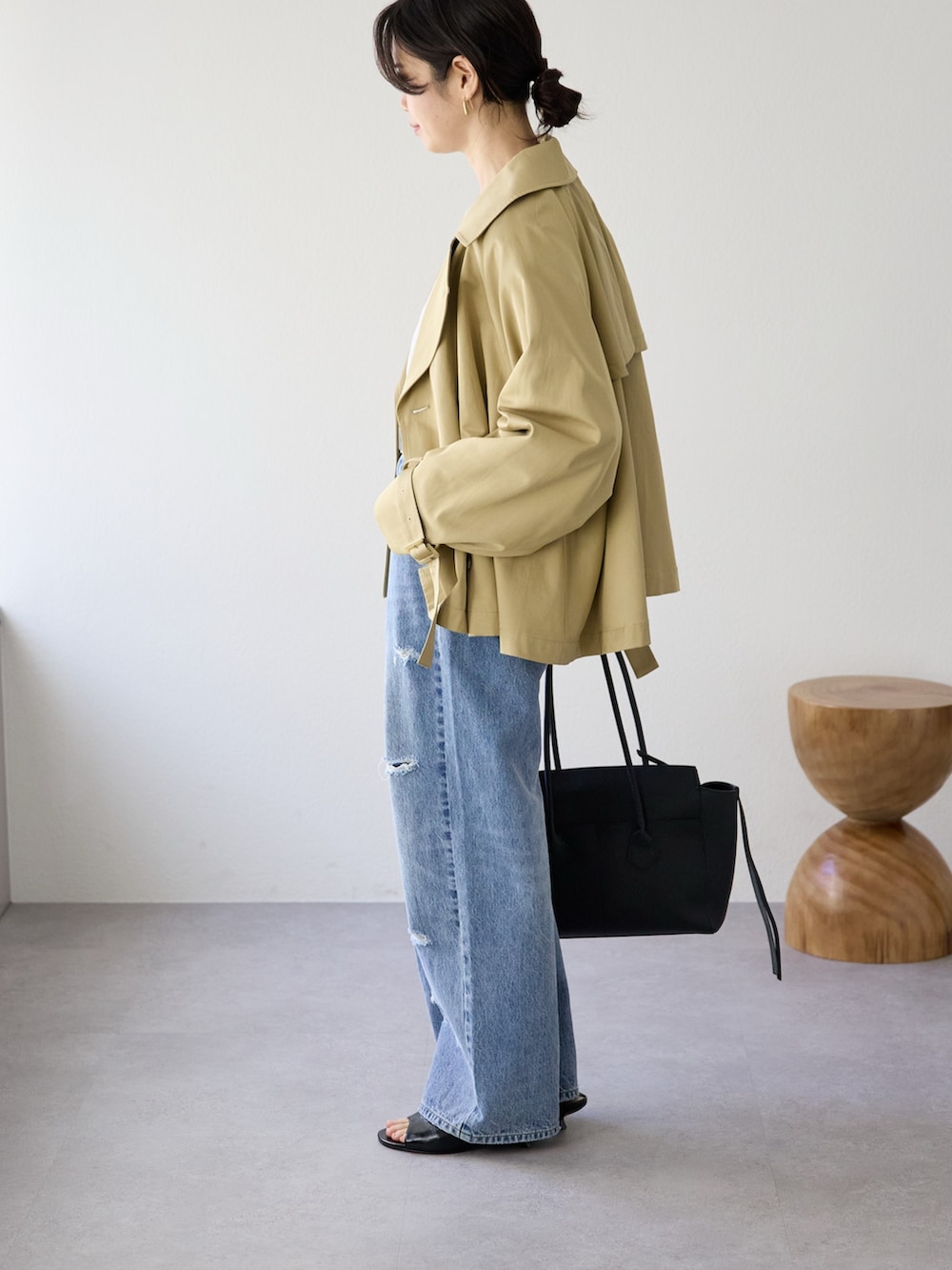 ベージュ系のトレンチコート、ホワイト系のTシャツ/カットソー、ブルー系のデニムパンツを着用したレディースの冬コーディネートの2枚目の写真