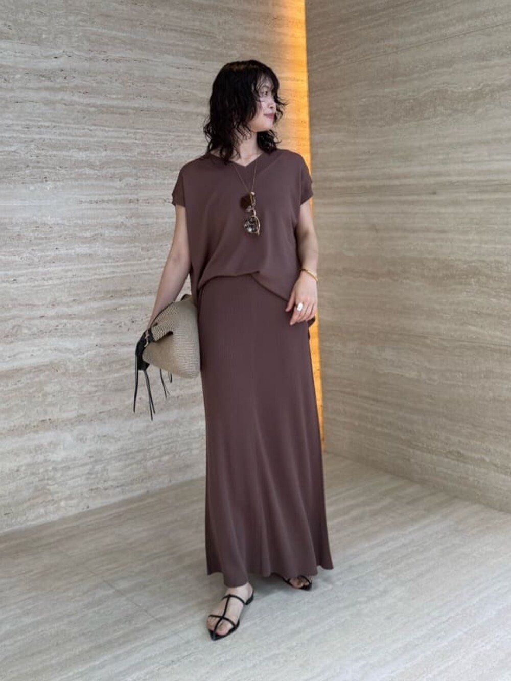 ブラウン系のスカート、ブラック系のトートバッグ、ブラウン系のニット/セーターを着用したレディースの夏コーディネートの2枚目の写真