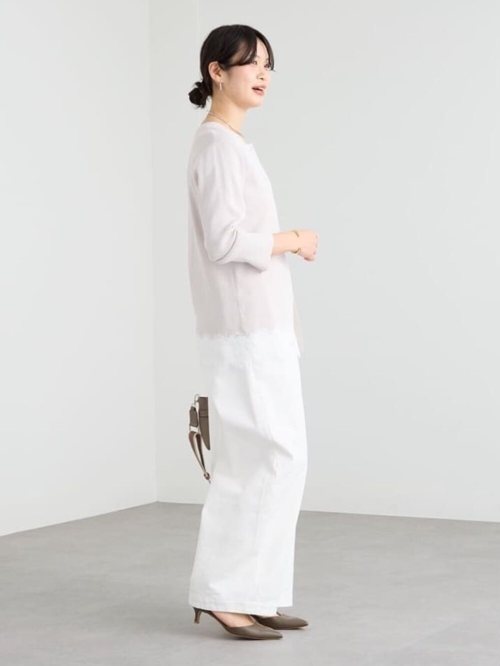 グレー系のトートバッグ、ホワイト系のデニムパンツ、グレー系のその他シューズを着用したレディースの冬コーディネートの2枚目の写真