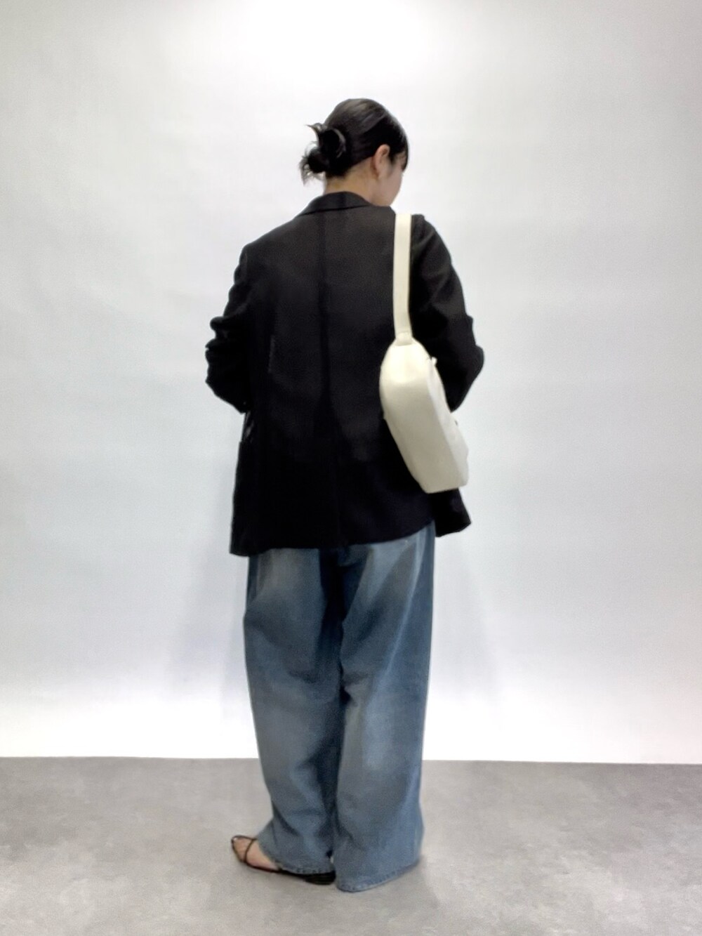 ブルー系のデニムパンツ、グレー系のテーラードジャケット、ホワイト系のキャミソールを着用したレディースの春コーディネートの3枚目の写真