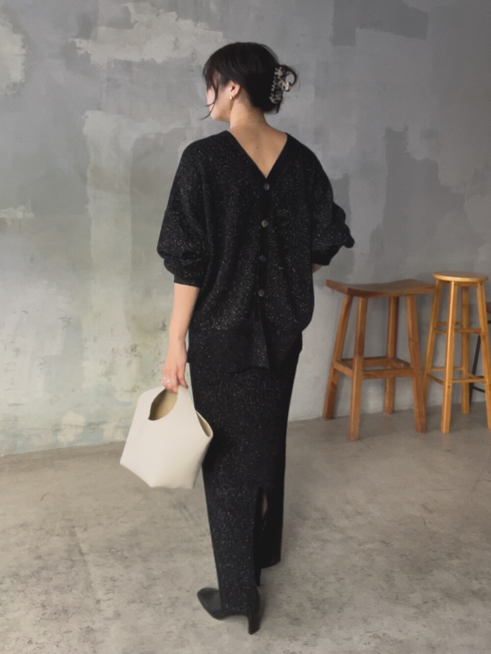 ブラック系のニット/セーター、ブラック系のスカート、ホワイト系のハンドバッグを着用したレディースの秋コーディネートの5枚目の写真