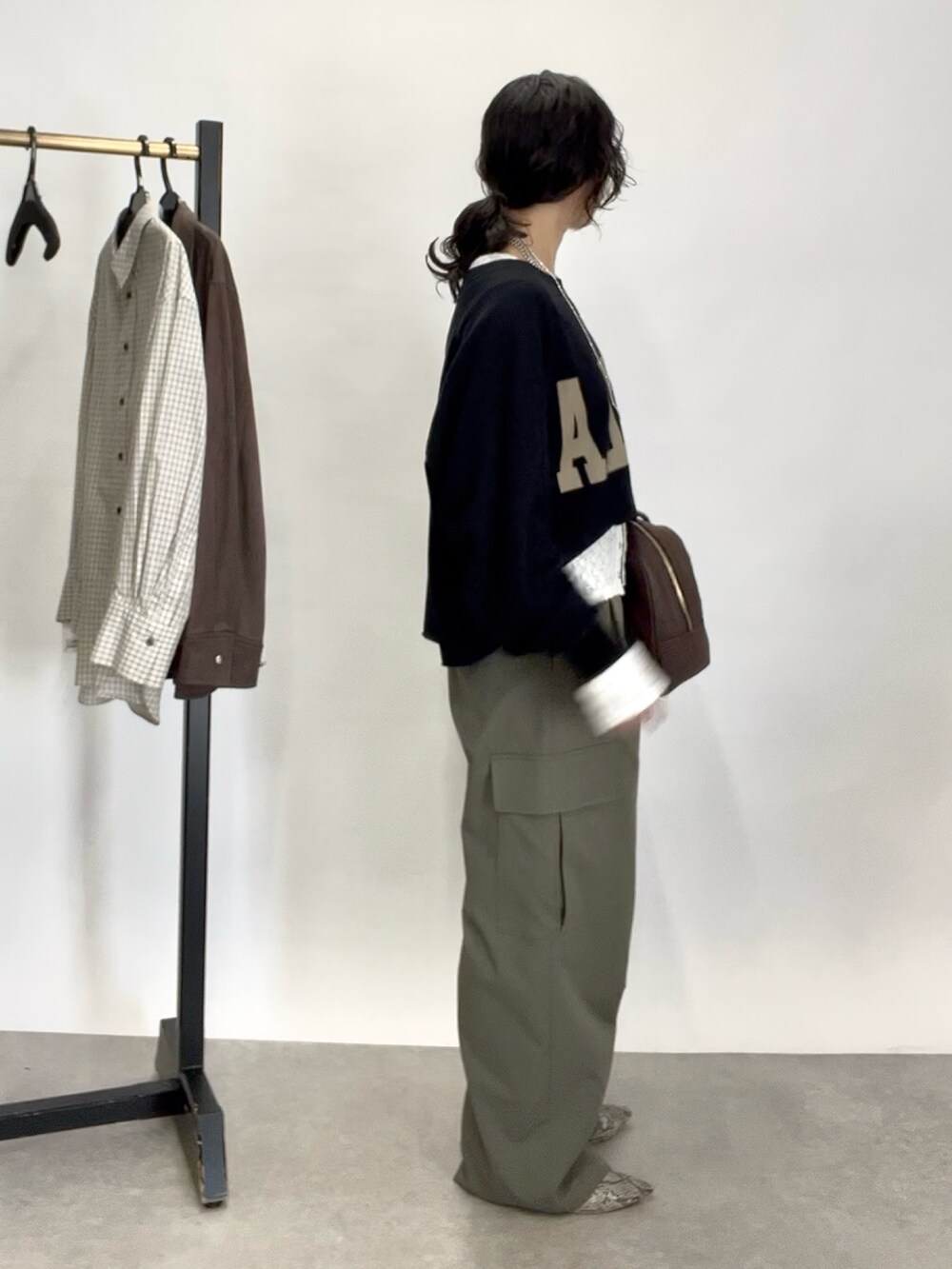 グリーン系のカーゴパンツ、グレー系のパンプス、ブラウン系のボストンバッグを着用したレディースの秋コーディネートの3枚目の写真