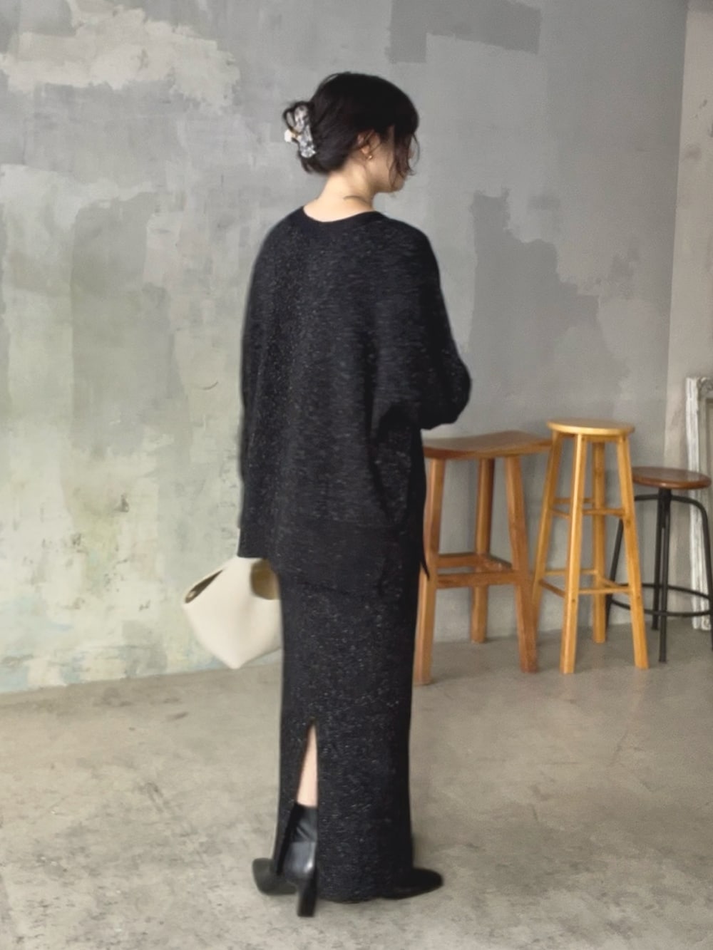 ブラック系のニット/セーター、ブラック系のスカート、ホワイト系のハンドバッグを着用したレディースの秋コーディネートの3枚目の写真