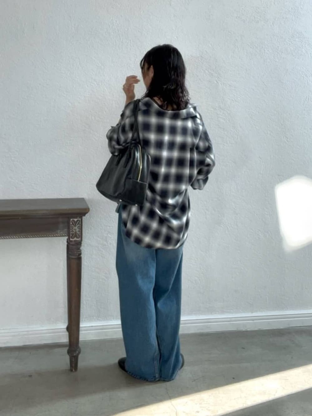 ブルー系のデニムパンツ、ブラック系のローファー、ブラック系のボストンバッグを着用したレディースの夏コーディネートの4枚目の写真