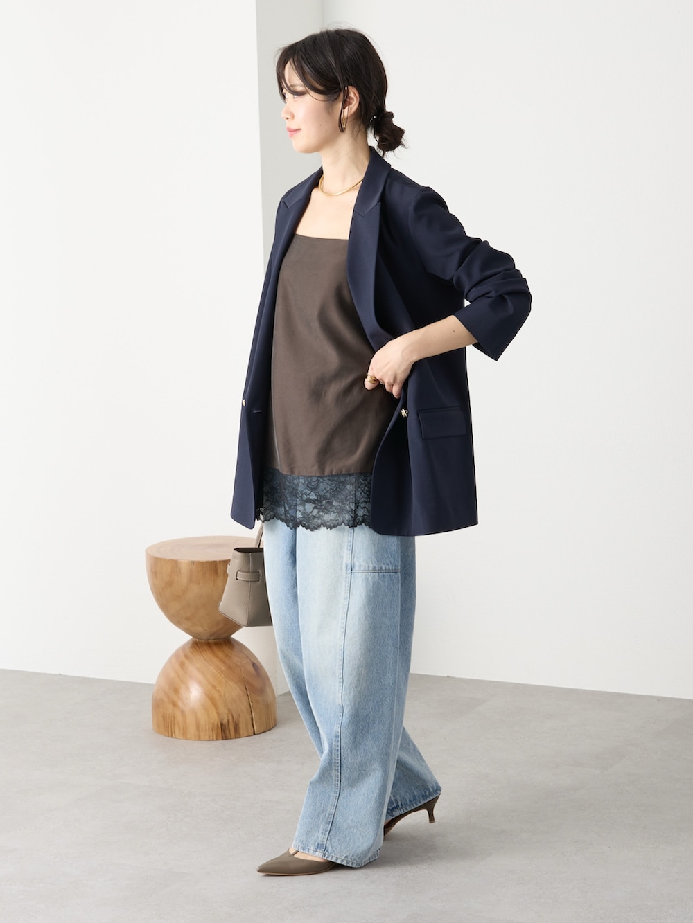 ブルー系のテーラードジャケット、ブラウン系のキャミソール、ブルー系のデニムパンツを着用したレディースの冬コーディネートの2枚目の写真