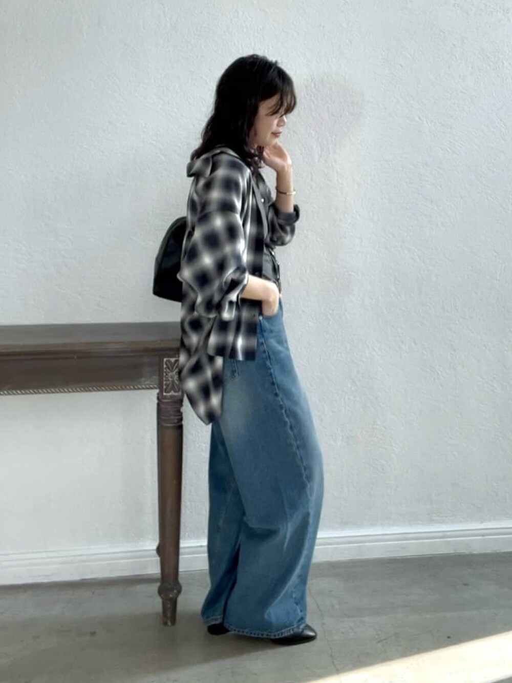 ブルー系のデニムパンツ、ブラック系のローファー、ブラック系のボストンバッグを着用したレディースの夏コーディネートの3枚目の写真